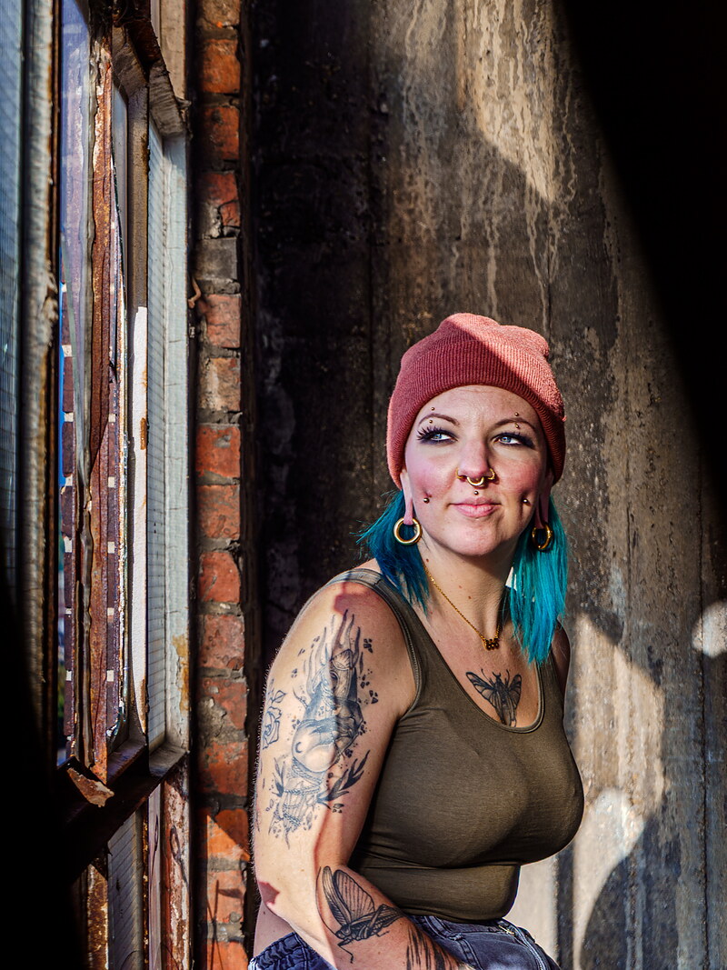 Sophie Guiot, tatoueuse à Andenne, bras tatoués, dans un décor industriel