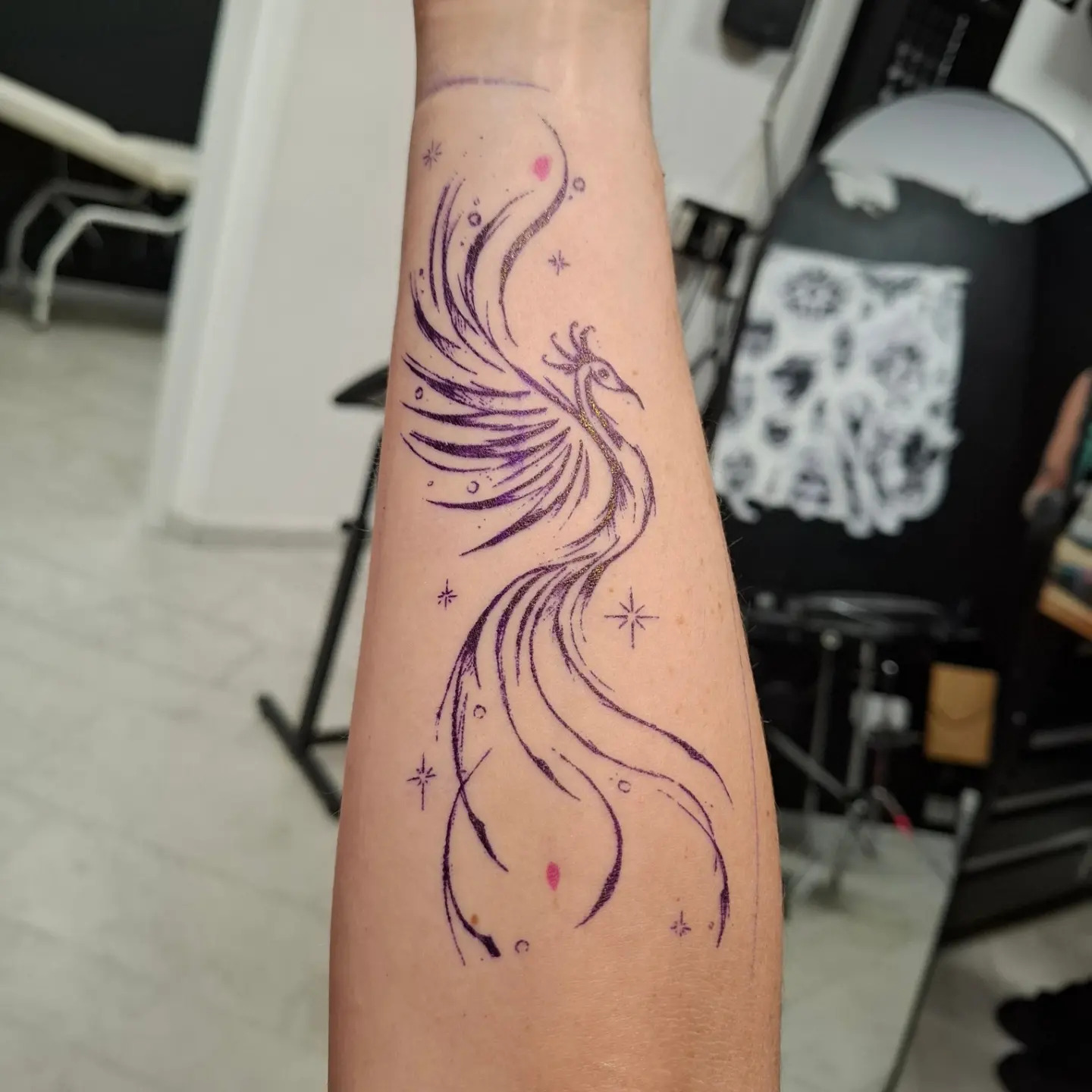 Tatouage fine line d’un phénix à l’encre violette, sur l’avant-bras, par Sophie Guiot